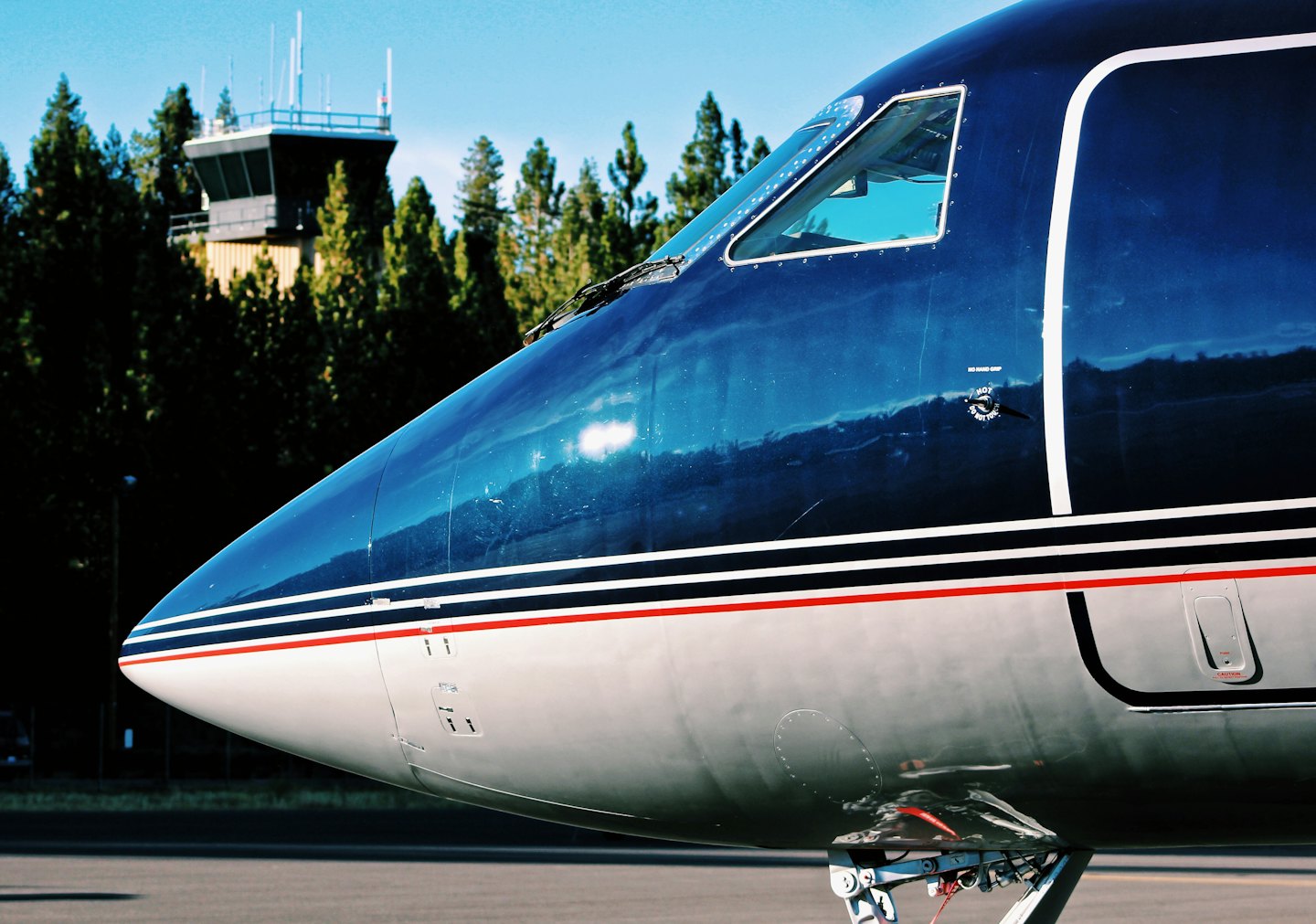 Privatflugzeug auf einem Flughafenrollfeld in der Nähe eines Turms geparkt.